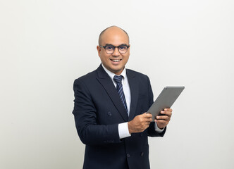 Portrait of Young asian businessman using digital tablet on isolated white background. Handsome middle aged Indian businessman holding tablet computer in office uniform.