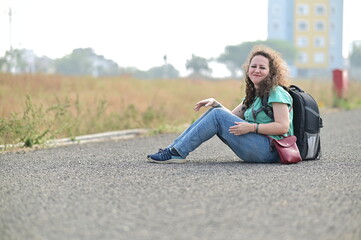 woman traveller sitting on the road. hiking deep into the wilderness, or going on tours with local experts. Woman traveler goes beyond city skylines and sweeping landscapes. Sitting for sometime in lo