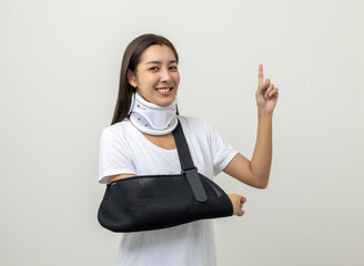 Happy young asian woman broken arm pointing finger on isolated background. Female put on plaster...