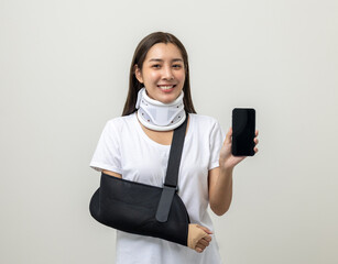 Happy young asian woman broken arm holding smartphone. Woman put on plaster cast splint with...