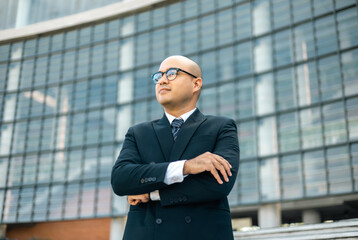 Senior manager business man in suit standing at the buildings downtown. Confident man arms crossed looking towards their goals for success. Executive business man