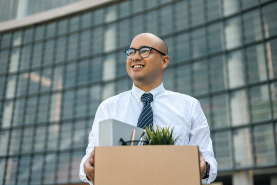 Employee first day working in the office. Happy Businessman with box cardboard personal item getting new jobs. Young man start working new office standing at building.