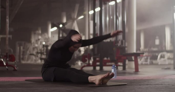 Muslim sportswoman warming up in gym