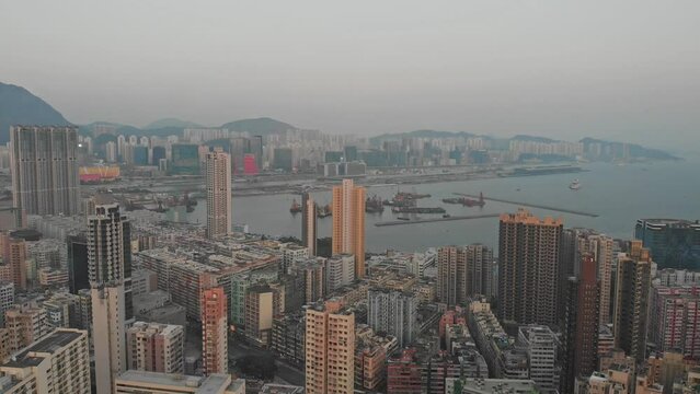 Kowloon side of Hong Kong. Aerial drone flight revealing tall buildings in city. High view during sunset. Golden hour. Asia. China.