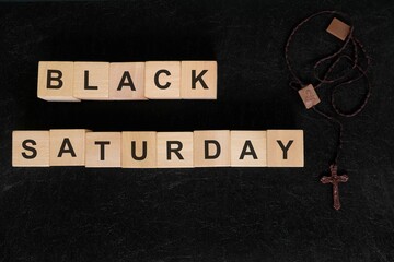 Black Saturday holy week concept. Wooden blocks typography with rosary flat lay in dark background.