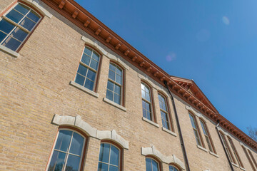 Low angle view of a building with bricks and paned windows in Austin, Texas. Building exterior with brown roof dentils against the clear blue skies.