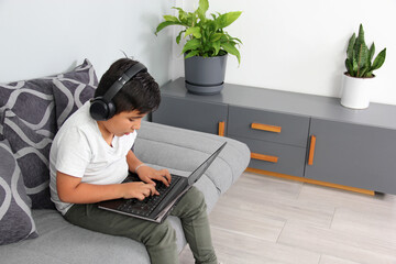 9-year-old Hispanic boy plays video games on his laptop with headphones leading to being overweight...