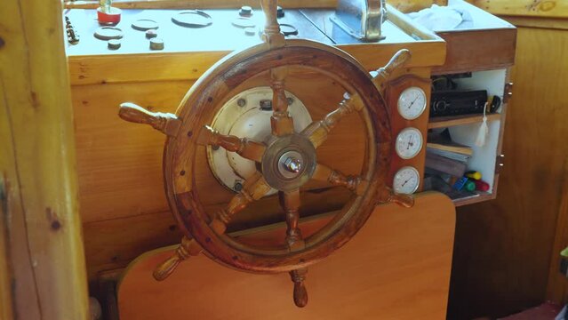 Close-up of wooden steering wheel and instruments on a pleasure boat. Tourist water transport for travel. Wooden vessel with steering wheel. Summer vacation. Slow motion