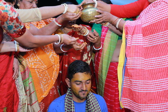 Hindu religious asian groom having bath by her aunts in his pre wedding ceremony, turmeric on the body is a hindu ritual before the big wedding day 