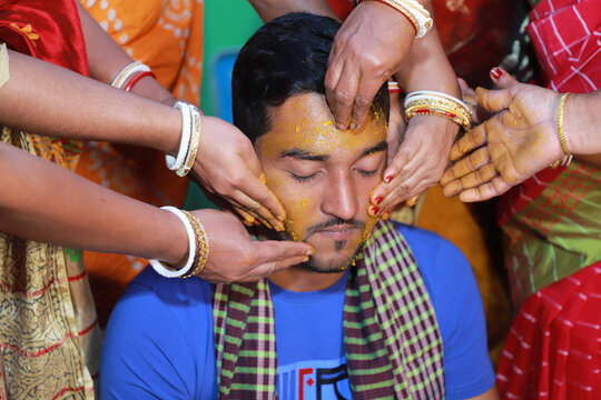 Hindu religious asian groom having bath by her aunts in his pre wedding ceremony, turmeric on the body is a hindu ritual before the big wedding day 