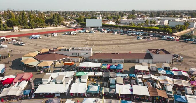 Discover the vibrant energy of Paramount's swap meet and experience the nostalgia of a drive in movie with a towering screen in this lively time lapse drone video