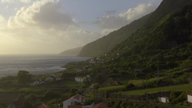 rural coastal village and crop fields in lush green cliffs, Faj&atilde; dos Vimes, S&atilde;o Jorge island, the Azores, Portugal