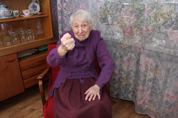 Stylish elderly woman hipster with an evil face shows a fig. Concept protest and objection of an...