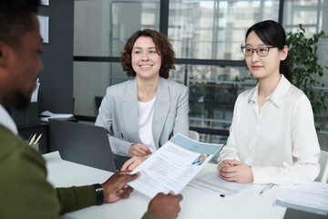 African American manager examining resume of candidate at table during a meeting in modern office