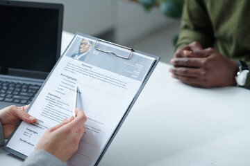Close-up of interviewer examining resume of candidate for a new post during job interview