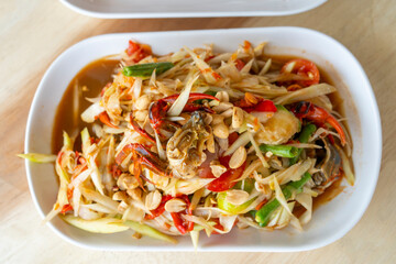 Delicious Som Tam -Thai green papaya salad with green beans,
 tomatoes, peanuts. Thai street food . Healthy vegan food