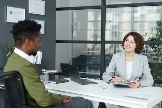 Young manager talking to candidate with disability during job interview in modern office