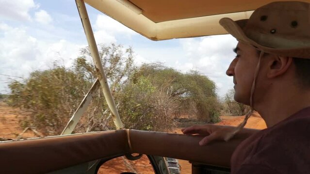 man on jeep driving trough african savannah, safari tour, green nature landscape, kenya, tsavo east