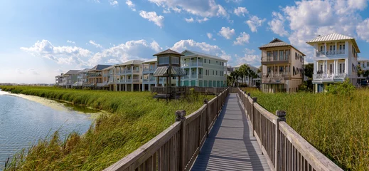 Crédence de cuisine en verre imprimé Descente vers la plage Wooden boardwalk with gazebo at the front of the homes on the beach at Destin Point, Destin, Florida. Views of the lake on the left with grass on the shore below the wooden path heading to the houses.
