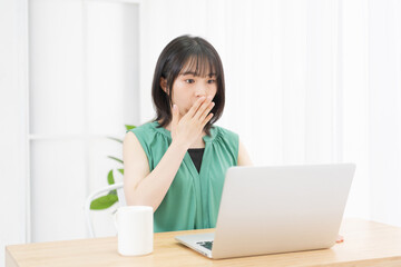 PCを使いながら驚いている若い女性