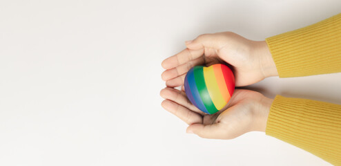 LGBT symbol.International Day Against Homophobia, Transphobia and Biphobia. May 17.Heart with rainbow LGBT flag in the hands on white background. Stop Homophobia. banner or greeting card.