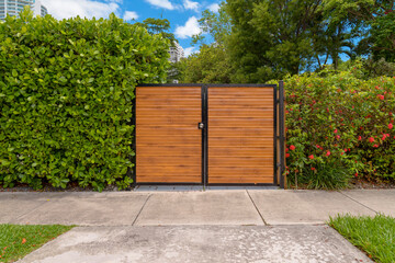 Home entrance driveway gate with wood slats in Miami, Florida. Gate of a residence in the middle of...