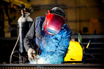 Worker with mask welds details with semi automatic machine