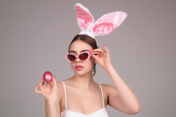 Beautiful young woman with bunny ears on studio color background. Easter funny woman with rabbit...