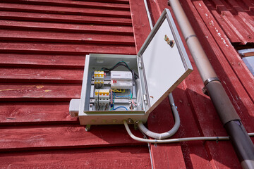 An external switchboard with an electric meter hangs on wall of wooden country house.
