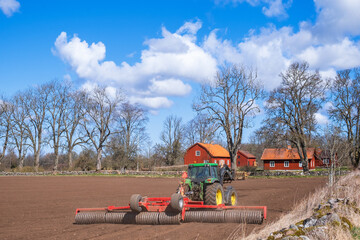 Field with a tractor working with a cultipacker at spring