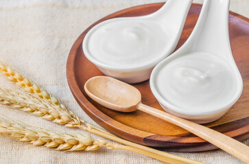 The Greek yogurt in a bowl and dry barley on tablecloth.