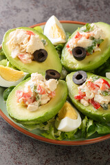 Palta reina is a delicious Chilean dish that consists of chicken salad on a halved avocado closeup on the plate on the table. Vertical