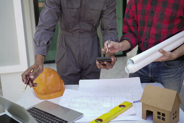 Smiling young architect or engineering builder in hard hat with tablet over group of builders at...