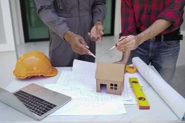 Smiling young architect or engineering builder in hard hat with tablet over group of builders at...