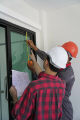 Smiling young architect or engineering builder in hard hat with tablet over group of builders at...