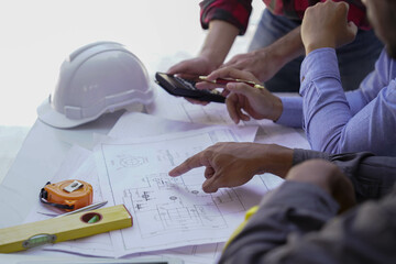 Smiling young architect or engineering builder in hard hat with tablet over group of builders at...