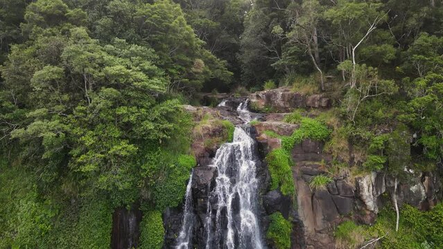 Unique view as water flows from a natural creek bed as it tumbles over moss covered waterfall. drone view