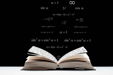 An open book, a textbook lies on the table. Metematic signs and formulas on a black background. The study of mathematics, algebra, geometry.