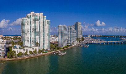 Fototapeta na wymiar Buildings and highway over the Intracoastal Waterway in Miami Beach Florida. Scenic urban landscape with city skyline against blue sky, clouds, and manmade inland water channel.