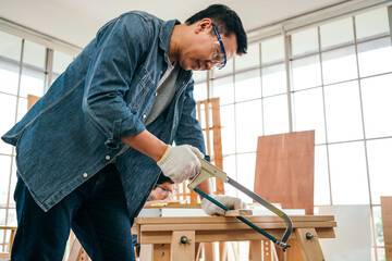 Asian father and son work as a woodworker or carpenter, Father wears safety goggles and saw a...