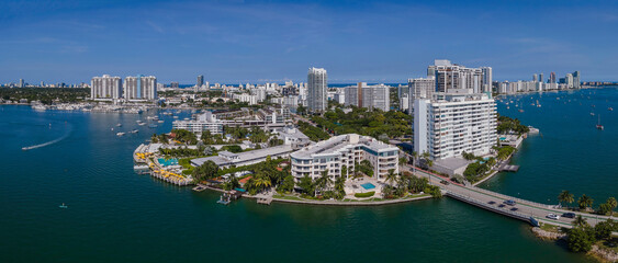 Obraz na płótnie Canvas Modern buildings on a curved land in an intracoastal area at Miami Beach, Florida. Panorama of city buildings in the middle of blue waters and views of blue sky at the background.