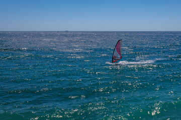 Windsurfer rushes on the blue sea waves