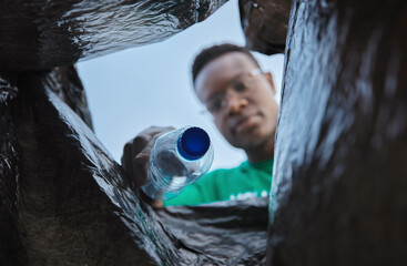 Recycle, bottle and black man with view in bag, sustainability and cleaning plastic pollution, earth day and community service. Saving the environment, charity and people putting trash in garbage bin