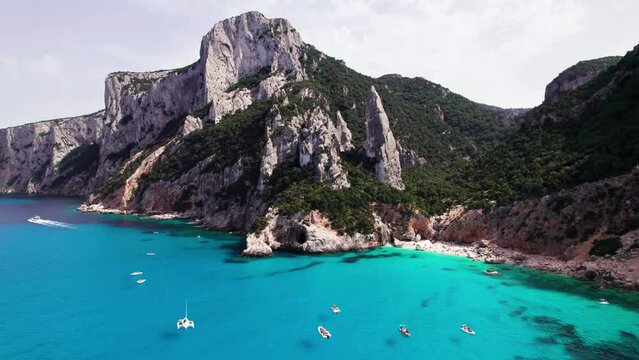Aerial view of tourist boat on turquoise sea on rock coast, Sardinia