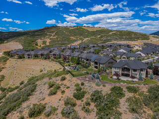 Fototapeta na wymiar Aerial view of a small neighborhood on a mountain at Draoer, Utah. Villas in a subdivision on mountain slopes against the vivid sky background.