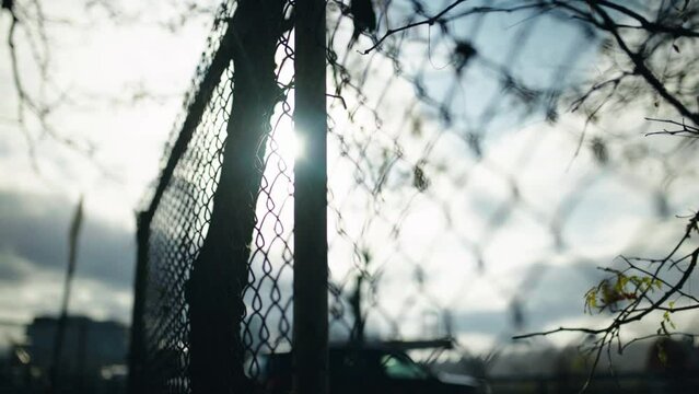 Chain link fence and blue sky behind them. Slowly moving along iron fence boundary of the jail restricted area or wall of the military camp. Loopable 3d animation concept of freedom restriction.
