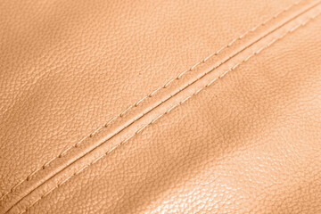 Car brown leather interior. Part of orange perforated leather car seat details with white...