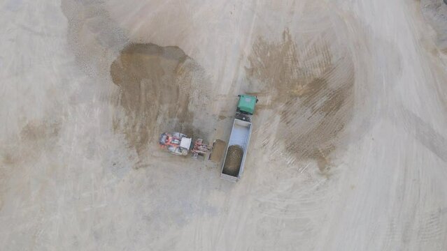 Top Down Aerial View of Loader Loading Crushed Stone Into Truck, High Angle Drone Shot