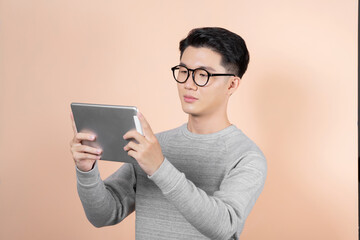 Portrait of a happy casual man using tablet computer over beige background