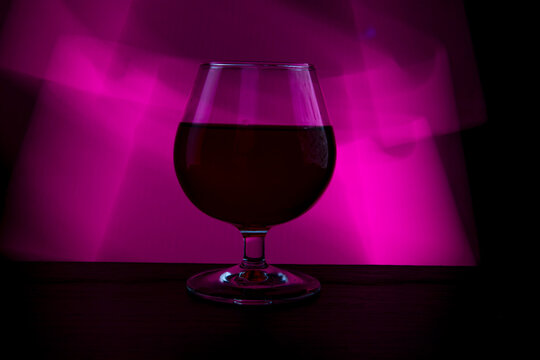 A glass of wine on a colored background.